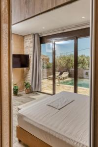 a bedroom with a bed and a sliding glass door at Olive Luxury Suites - ADULTS ONLY in Kamilari +38 photos