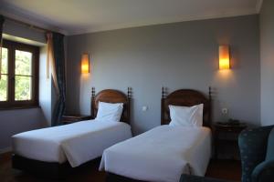 two beds in a hotel room with white sheets at Hotel do Elevador in Braga