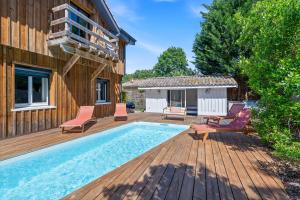 a swimming pool on a wooden deck next to a house at Villa typique - piscine et terrasse in La Teste-de-Buch