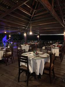 a restaurant with white tables and chairs and a man on a stage at Gran Lençóis in Barreirinhas