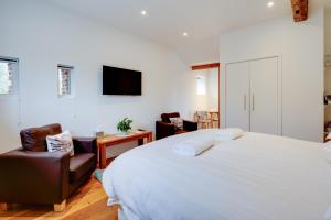 a bedroom with a large bed and two chairs at The Suites at Pannells Ash in Castle Hedingham