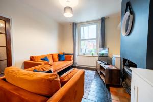 a living room with two orange couches and a tv at 3 BD 5 Beds WiFi in Wellingborough