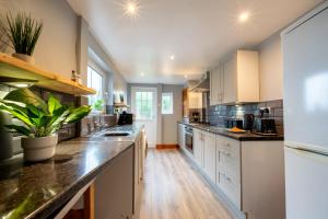 a large kitchen with white cabinets and black counter tops at 3 BD 5 Beds WiFi in Wellingborough