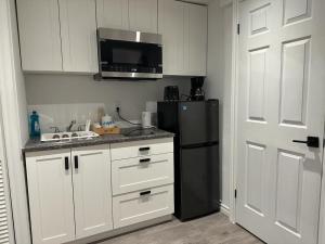 a kitchen with white cabinets and a black refrigerator at Mill pond cozy and private 2 in Richmond Hill