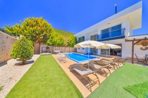 a house with a swimming pool with chairs and umbrellas at Nergiz Villas in Kaş