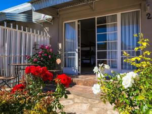a front door of a house with red and white flowers at Hazeldene Accommodation in Colesberg