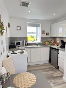 a kitchen with white cabinets and a sink at Altons Bothy Guest House in Kinmuck