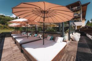 a row of beds with umbrellas on a deck at Hotel Kaprunerhof in Kaprun