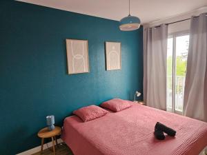 a bedroom with a pink bed and a blue wall at Quai de la Gare, Appartement étape, 2 chambres, face à la Gare in Châtellerault