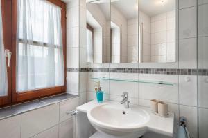 a white bathroom with a sink and a mirror at Haus Baden in Hagnau +55 photos