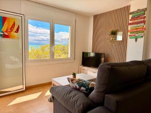 a living room with a couch and a tv and a window at Roses Beach in Roses
