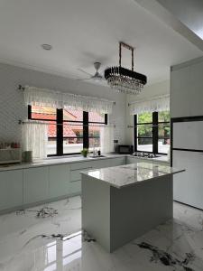 a white kitchen with a island in the middle at Elite Cozy Home 5BR5B, BBQ, Karaoke, Netflix, Near MITC in Ayer Keroh