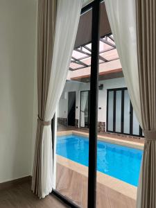 a view of a swimming pool through a window at Elite Cozy Home 5BR5B, BBQ, Karaoke, Netflix, Near MITC in Ayer Keroh +8 photos