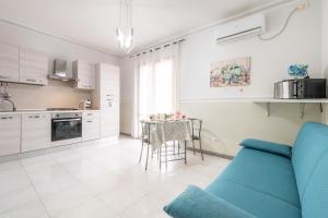 a living room with a blue couch and a kitchen at Piccola Casa Melis in Capoterra