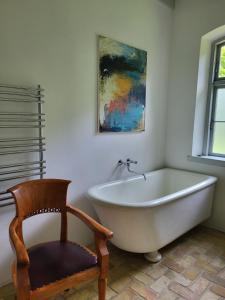 a white bath tub in a bathroom with a chair at Inseldomizil Brummers Gaard in Haderslev +29 photos