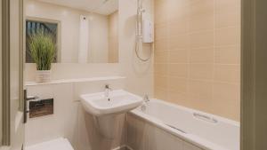 a white bathroom with a sink and a bath tub at Wansfell Cottage At Windermere Marina Village in Bowness-on-Windermere +12 photos