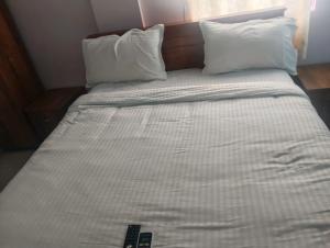 a bed with two pillows and a remote control on it at crown crest condos in Chengalpattu