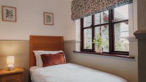 a bedroom with a bed and a window at Wansfell Cottage At Windermere Marina Village in Bowness-on-Windermere