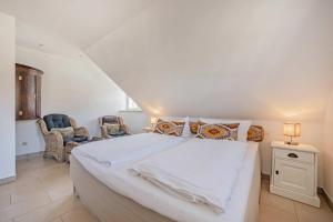 a bedroom with a large white bed and two chairs at Reethus am Küstenwald in Koserow