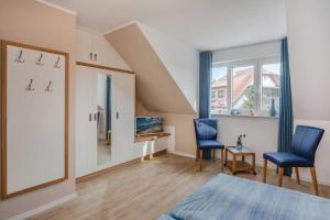 a bedroom with two blue chairs and a television at Usedom-Idyll in Loddin