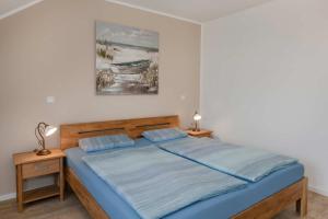 a bedroom with a bed with blue sheets and a painting at Usedom-Idyll in Loddin
