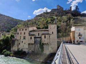 a castle on a hill next to a river at Gîte Le Devant De La Chaux in Pontaix