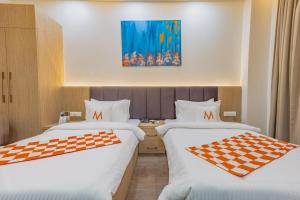two beds in a hotel room with a checkered checkerboard at Mosaic Connect Ayodhya in Ayodhya