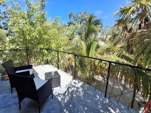 a balcony with a table and chairs and palm trees at Casa Pavezin in Mahahual