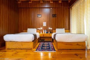 two beds in a room with wooden walls at Valley Resort in Jakar