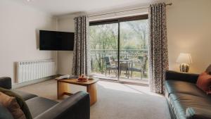 a living room with a couch and a large window at Wansfell Cottage At Windermere Marina Village in Bowness-on-Windermere