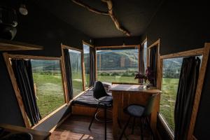 a room with three windows and a desk and chairs at Kajuta in Betliar