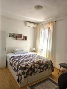 a bedroom with a bed with a checkered blanket at Apartmani Banić Apartman Studio 3 in Postira