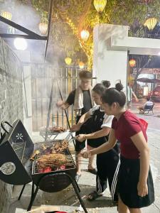 a group of people cooking food on a grill at Khế Homestay Phố Cổ Ninh Bình in Ninh Binh