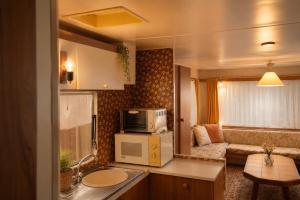 a small kitchen with a microwave and a living room at Belgian GP 2026 Fast Access The Hilltop Lodge in Amblève