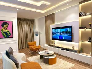 a living room with a television and a couch and a table at Luxury 1 BR With Swimming Pool & 24 Hours Security In Lekki 1 in Lagos