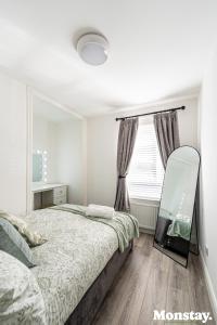 a bedroom with a bed and a mirror and a window at Walled City House in Derry Londonderry