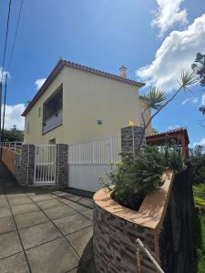 a white house with a fence and a yard at Lúcia's House in Santa Cruz