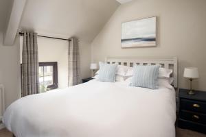 a bedroom with a large white bed and a window at Town Farm Cottages Beadnell by Coast & Country Stays in Beadnell