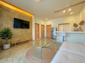 a living room with a couch and a tv on a wall at Thara Pearl Villa in Ko Phangan