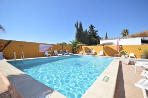 a large swimming pool with chairs and a building at Casa Samuel con piscina comunitaria y porche in Cádiz +11 photos