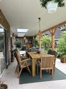 a wooden table and chairs on a patio at Bed&Breakfast Kamersven in Maarheeze