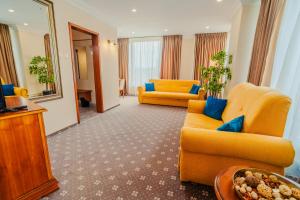 a living room with yellow furniture and a mirror at Hotel Trotuş in Onești