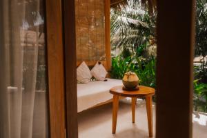 a porch with a bed and a table and a window at Luana Lombok in Selong Belanak