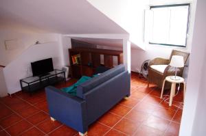 リスボンにあるLisbon Sloped Ceiling Apartmentのリビングルーム(青いソファ、テレビ付)