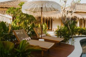 two chairs and an umbrella on a deck next to a pool at Luana Lombok in Selong Belanak +75 photos