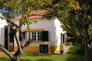 a white and yellow house with trees in front of it at Verdizela Pool & Barbecue Villa in Corroios