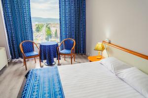 a bedroom with a bed and two chairs and a table at Hotel Trotuş in Onești +151 photos