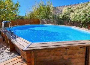 a large swimming pool with a wooden deck around it at La Maison Bleue in Rustrel