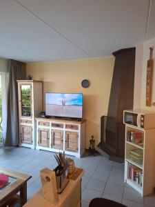 a living room with a flat screen tv on a wall at Huus Kompass - Familienurlaub mit Hund nahe am Nordseestrand in Butjadingen +5 photos