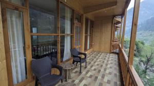a room with windows and chairs on a balcony at Jibhi Dreams in Jibhi